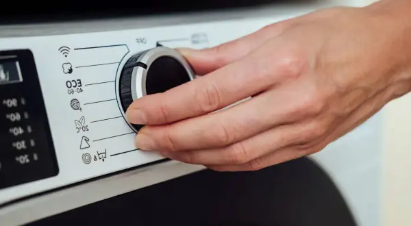 Dłoń kręci pokrętłem pralki Whirlpool. Rozwiązywanie problemów z instrukcją obsługi.
