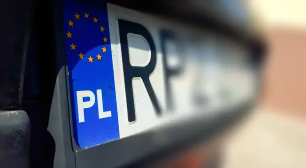 Zbliżenie na polską tablicę rejestracyjną z symbolem UE. Czas na przerejestrowanie samochodu i nowe oznaczenia.