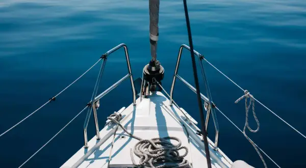 Prua di una barca a vela su un mare blu calmo. La prevalenza di una pompa è un concetto che non si applica a questa immagine.
