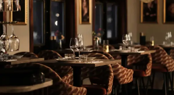 Mysig atmosfär på en av Stockholms nya restauranger. Dukade bord med glas och bestick, ombonade stolar och konst på väggarna.