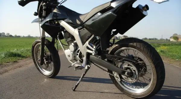 Czarny motocykl typu supermoto, gotowy do jazdy po wiejskich drogach. Senda czeka na przygodę.