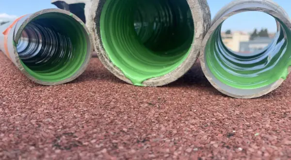 Trois tuyaux en PVC, dont un avec un revêtement vert vif, prêts pour enlever calcaire canalisation pvc.
