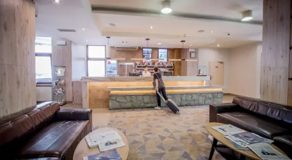 Recepcja hotelu Diament Wisła. Gość z walizką przy ladzie. W holu wygodne kanapy i stoliki z prasą.