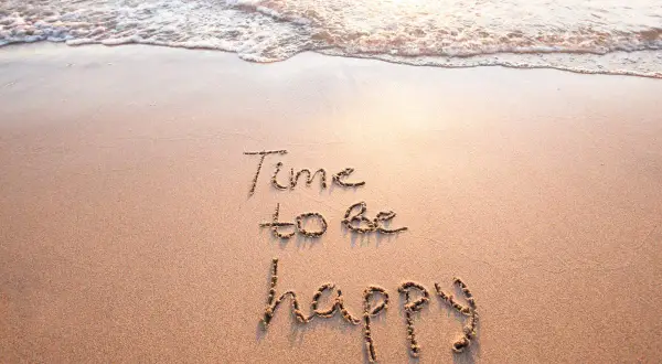 Sand mit Wellen und der Aufschrift "Time to be happy". Ein Moment des selig seins.