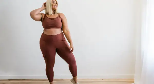 Kobieta plus size w brązowym komplecie sportowym, legginsy z kieszeniami.