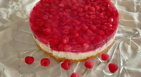 Himbeer-Curd-Torte mit frischen Himbeeren und glänzender Tortenguss-Schicht auf einem cremigen Boden. Ein Genuss für Augen und Gaumen.