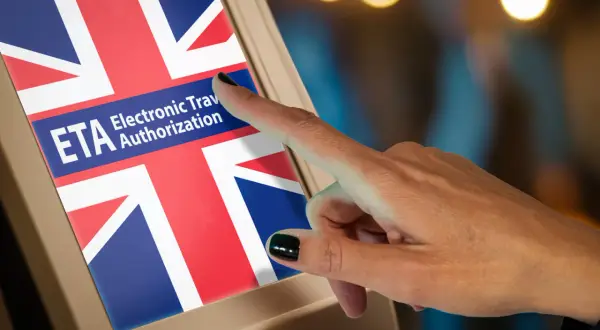 Palec dotyka ekranu z flagą Wielkiej Brytanii i napisem "ETA Electronic Travel Authorization". To krok do uzyskania wizy do Londynu.