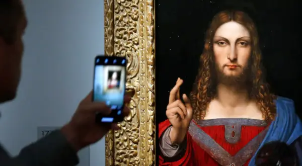 Osoba robi zdjęcie telefonem komórkowym obrazu "Salvator Mundi" przedstawiającego Jezusa.