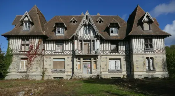Maison abandonnée en Normandie, typique de l'urbex. Façade en colombage et pierre, toiture pentue, fenêtres brisées.