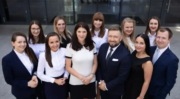 Grupa prawników w garniturach i strojach biznesowych przed budynkiem.