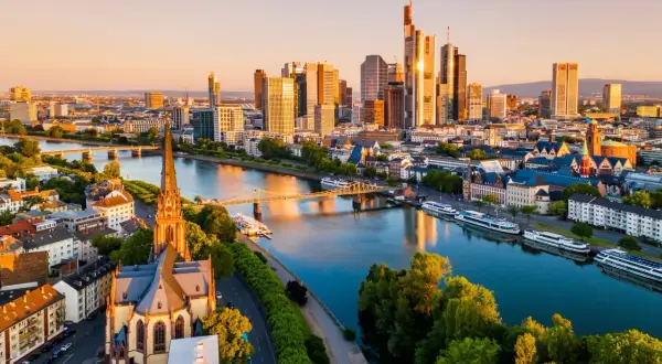 Widok na nowoczesne wieżowce i zabytkowy kościół nad rzeką Men. Tak wygląda Frankfurt o zachodzie słońca.
