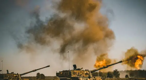 Dwa czołgi strzelają, tworząc kłęby dymu i ognia. Scena wygląda jak ćwiczenia, ale można by pomyśleć o "friendly fire".