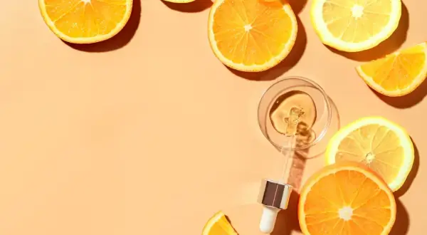 Krople serum z witaminą C w pipetce, otoczone plasterkami pomarańczy i cytryny. Pamiętaj, z czym nie łączyć witaminy C.