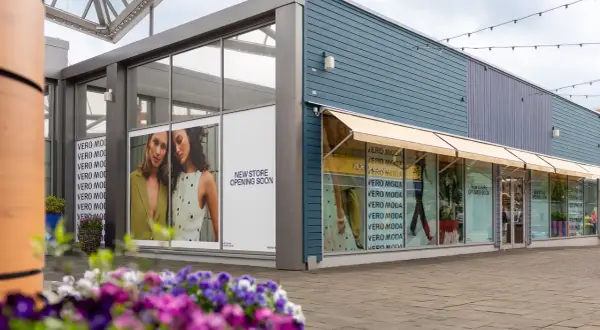 Vero Moda outlet med skyltar som visar "New Store Opening Soon". Blommor i förgrunden.