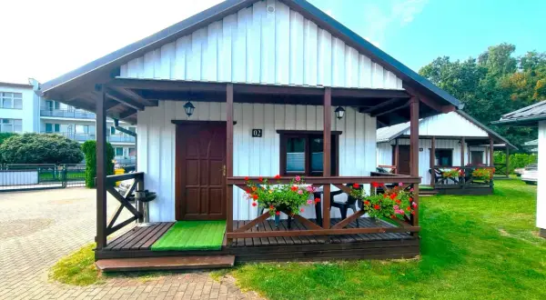 Urocze domki letniskowe Amber House z werandą i kwitnącymi pelargoniami. Idealne miejsce na wypoczynek.