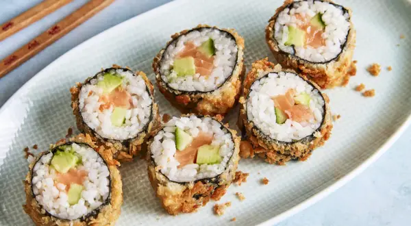 Knuspriges Tempura Sushi mit Lachs und Avocado auf einem Teller, bereit zum Genießen.