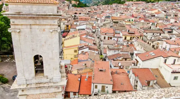 Vista dall'alto di San Marco in Lamis: un campanile in pietra domina un dedalo di tetti rossi e case arroccate tra le colline. Cosa vedere in questo borgo?