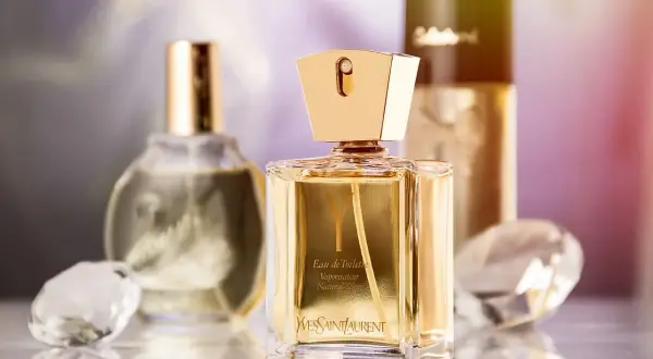 Złote flakony perfum Yves Saint Laurent i innych marek, kryształy i subtelne tło. Jaki alkohol do perfum? To pytanie zadaje sobie wielu miłośników zapachów.
