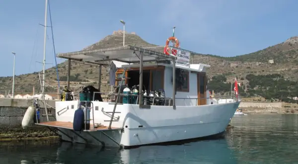 Barca da sub con bombole pronte per il battesimo dello scafo. Sullo sfondo, un castello su una collina.