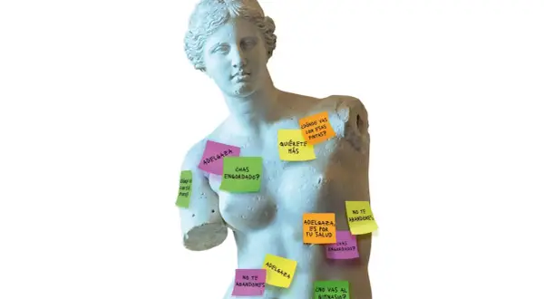 Estatuas clásicas cubiertas de notas adhesivas con mensajes sobre los **canones de belleza** y la presión por adelgazar.