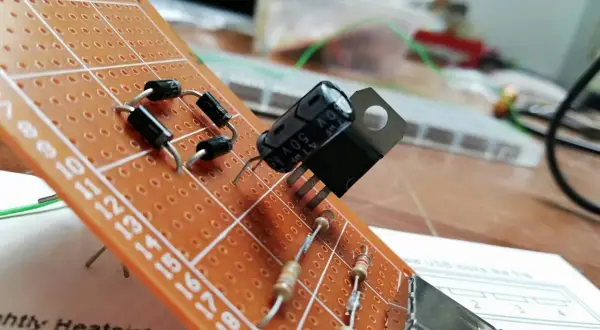 Układ elektroniczny na płytce stykowej z diodami, rezystorami i kondensatorem. Widać też element przypominający warystor.