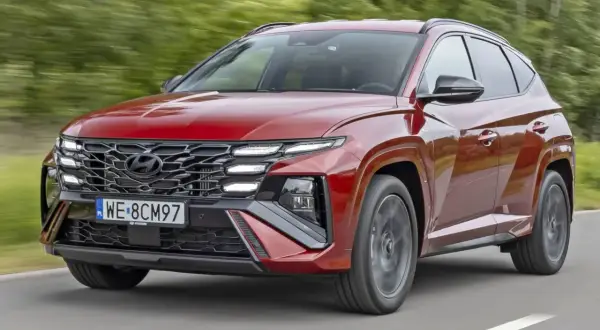 Czerwony Hyundai Tucson z charakterystycznym grillem i światłami LED pędzi po drodze. TCO.