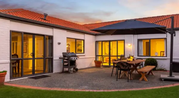 Beautiful house photography showcasing a patio with a BBQ, dining set, and umbrella, ready for entertaining.