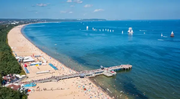 Brzeźno atrakcje: tłumy na plaży, molo, żaglówki i statki na morzu. Idealne miejsce na letni wypoczynek.