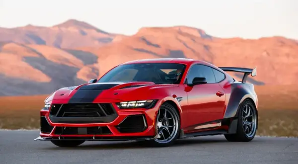 Czerwony Ford Shelby z czarnymi pasami i spojlerem na tle pustynnych gór.