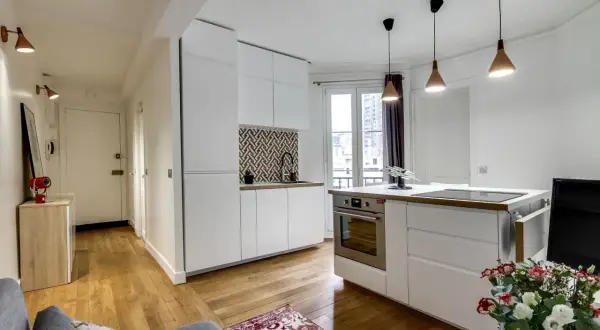 Moderne 50 qm Wohnung einrichten: Offener Wohnbereich mit weißer Küche, Holzboden und Flur.