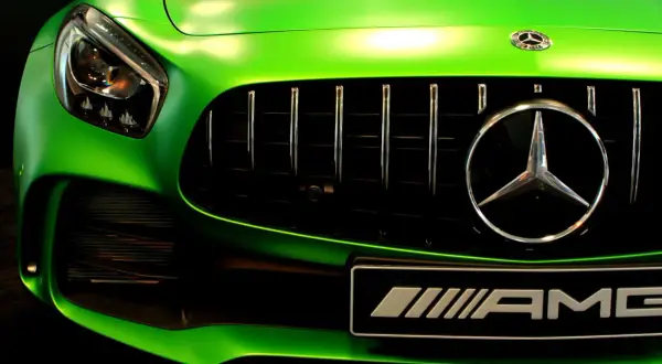 Zielony Mercedes AMG z błyszczącym chromem na grillu i emblematach.