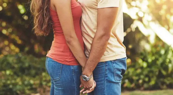Ett par håller varandra i händerna utomhus. Deras kläder antyder en åldersskillnad relation 20 år, men kärleken är tydlig.