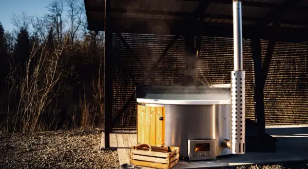Gorąca para unosi się z jacuzzi, podgrzewanego drewnem. Zastanawiasz się, jak długo nagrzewa się woda w jacuzzi? Czas zależy od wielu czynników.