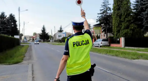 Policjant zatrzymuje ruch, by ukarać kierowcę za przekroczenie prędkości o 30 w terenie zabudowanym.