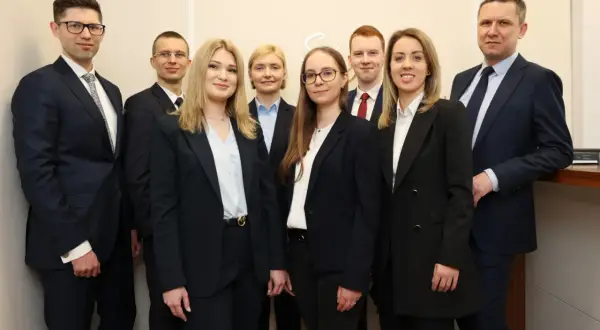 Grupa prawników w garniturach stoi w rzędzie.