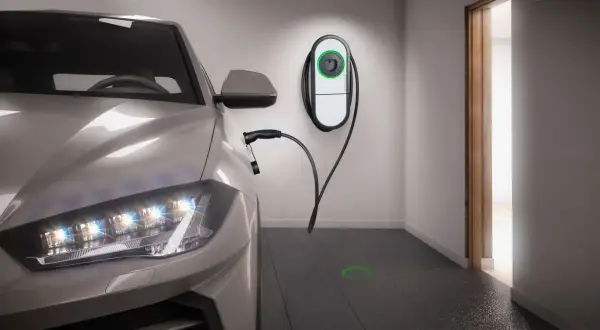 Auto elettrica in ricarica in un box privato. Stazione di ricarica a muro e cavo collegato. Luce verde sul pavimento indica la posizione.