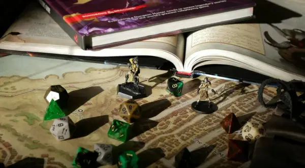 Księga D&D, kostki i figurki na mapie – wszystko gotowe na epickie gry RPG.