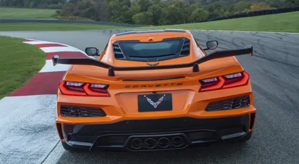 Pomarańczowy Corvette C9 z dużym spojlerem na torze wyścigowym.