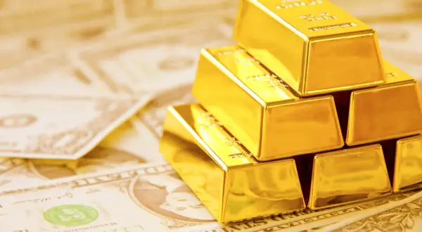 Złote sztabki ułożone na dolarach symbolizują globalne rezerwy złota i bogactwo.