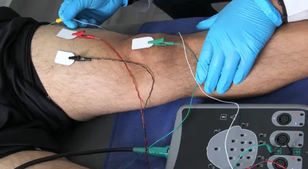 Elektrody podłączone do nogi pacjenta i aparat do badań.