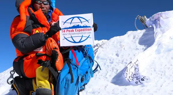 Kami Rita feiert auf dem Gipfel mit einem Schild der "14 Peak Expedition".
