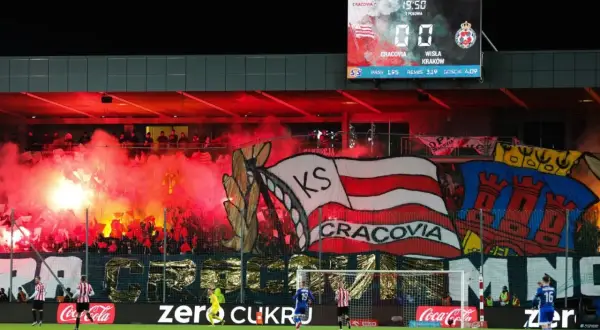 Oprawa kibiców najstarszego klubu piłkarskiego w Polsce, Cracovii, z racami i transparentami. Na tablicy wyników 0:0.