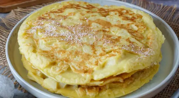 Ein gestapelter Apfelpfannkuchen, bestäubt mit Puderzucker. Ein köstliches Apfelpfannkuchen Rezept, das man ausprobieren muss!