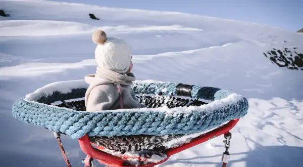 Kleines Kind im Schnee, bereit für den Winterurlaub mit Baby. Die Aussicht ist atemberaubend.