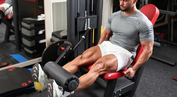 Mann trainiert den Beinstrecker Muskel an einem Gerät im Fitnessstudio.