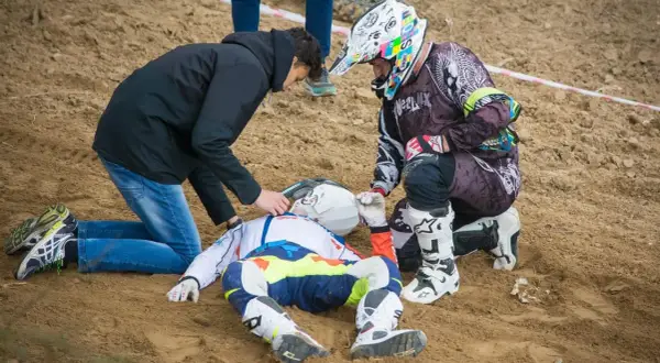 Po wypadku Tomasza Golloba, ratownicy udzielają pomocy leżącemu na piasku zawodnikowi w stroju motocyklowym.