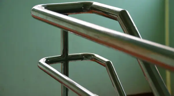 Precyzyjne gięcie rur stalowych na poręczy schodowej. Połyskujący metal tworzy elegancką formę.