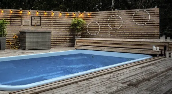 En avkopplande oas med en pool omgiven av en vacker trall. Ljusslingor och dekorationer skapar en mysig atmosfär.