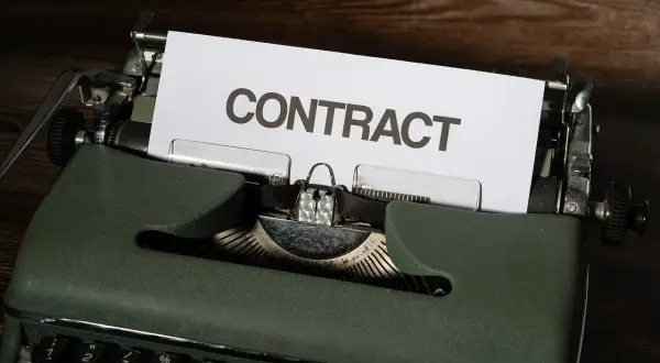 Stara maszyna do pisania z kartką z napisem "CONTRACT". Czas na wypowiedzenie umowy B2B.