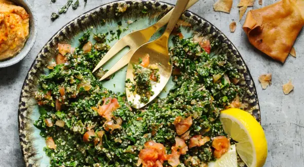 En fräsch tabbouleh med persilja, tomat och bulgur, serverad med citronklyftor och pitabröd. Ett perfekt tabbouleh recept för sommaren.